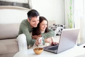 Our Priority Is You; Couple hugging in the living room looking at the computer