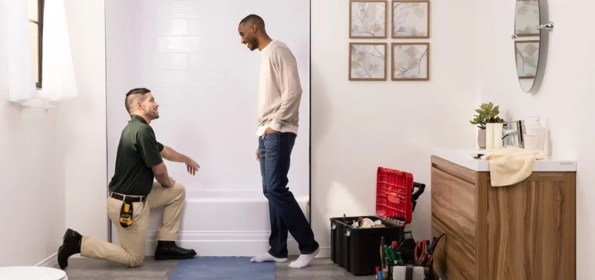 Man standing in bathroom while Bath Fitter employee performs budget-friendly bathroom remodel